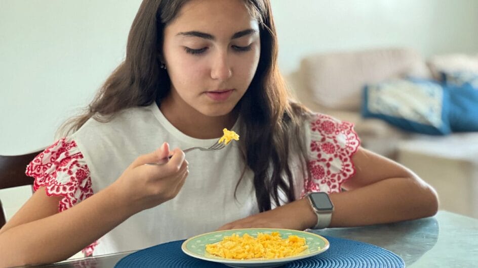 menina comendo ovos mexidos servidos em um prato