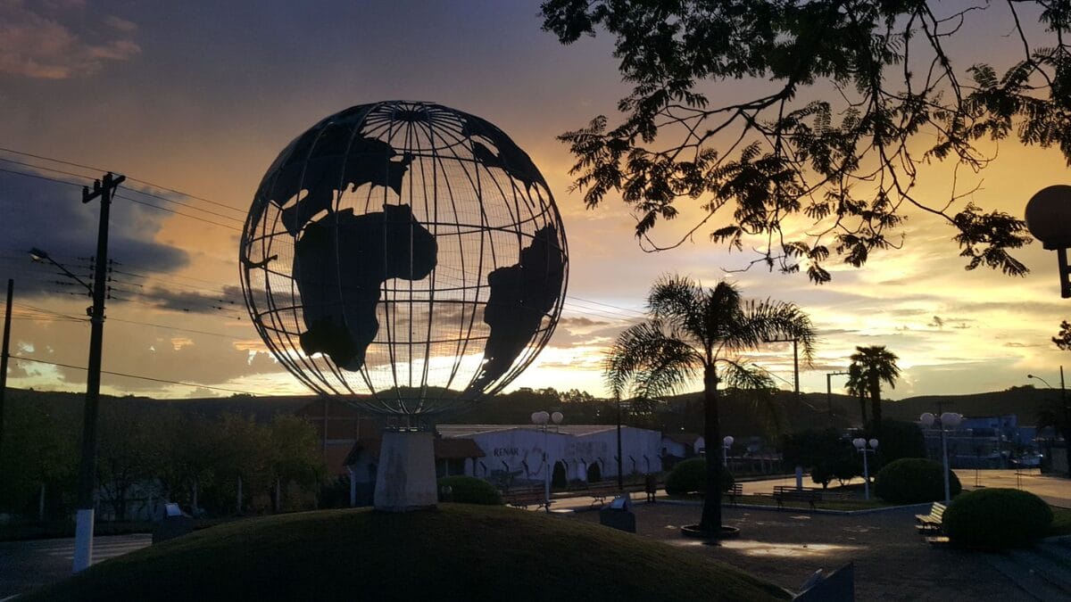 Pra&ccedil;a com globo gigante ao entardecer, em Fraiburgo