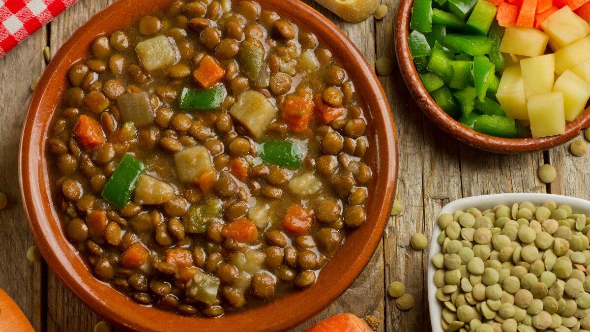 Lentilha cozida com legumes em tigela rústica, prato tradicional de Ano Novo associado à prosperidade e boa sorte.