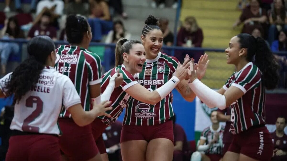 Atletas do Fluminense se cumprimentando sorrindo após marcar ponto