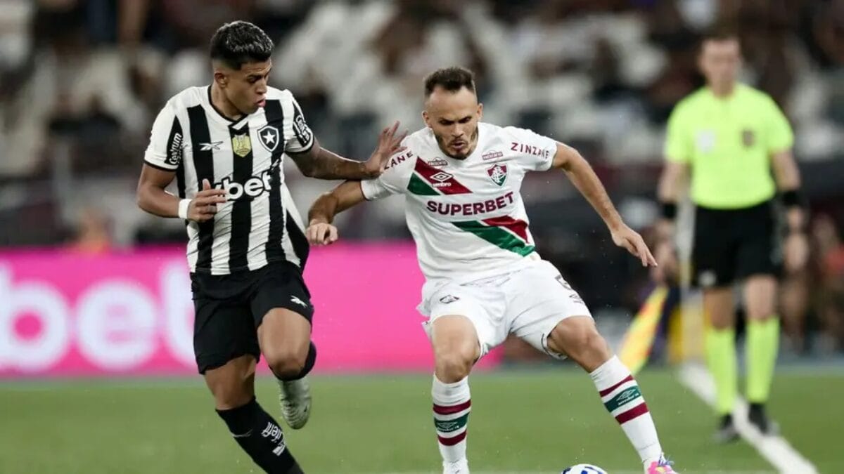 Atlestas de Fluminense e Botafogo em disputa de bola durante jogo.