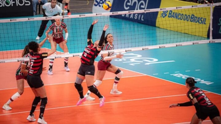 Jogadora do Flamengo levantando bola enquanto atleta do Fluminense se prepara para bloquear