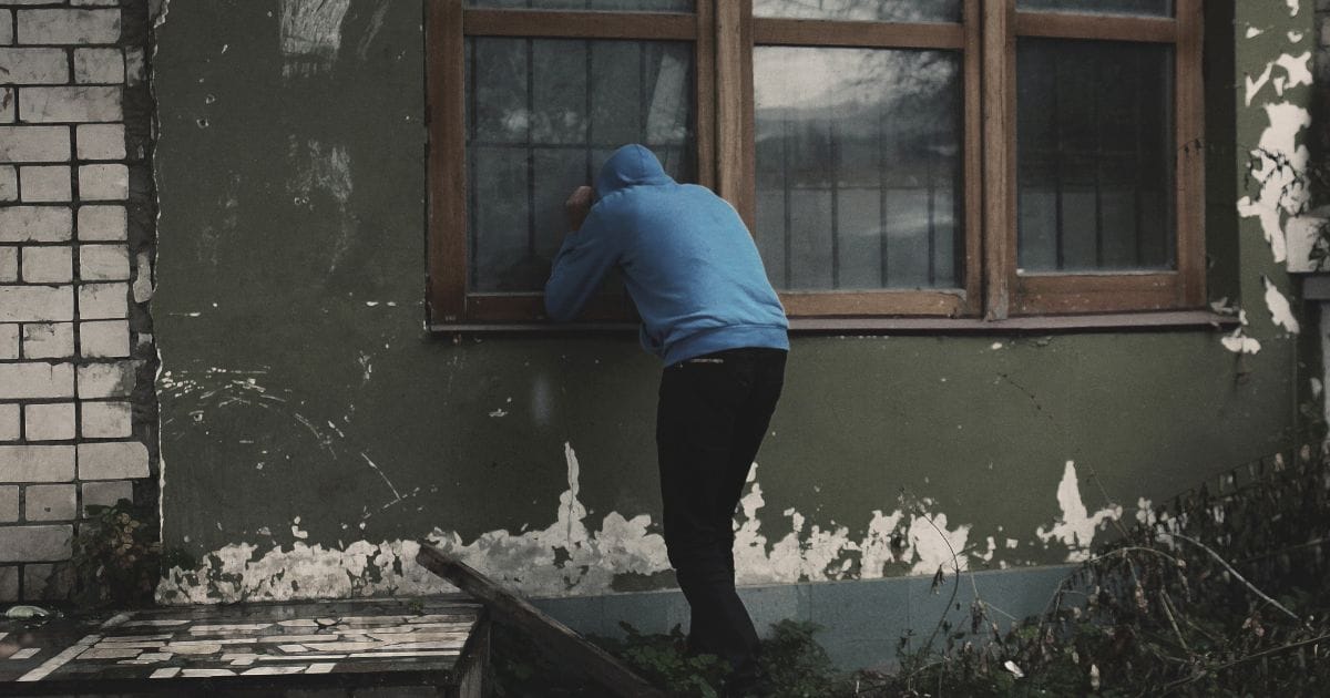 Homem invadindo uma casa pela janela