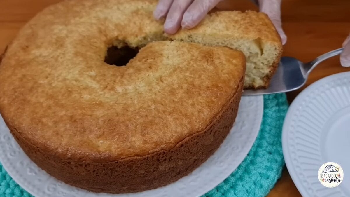 Fatia de bolo de amido de milho sendo retirada mostrando interior fofo