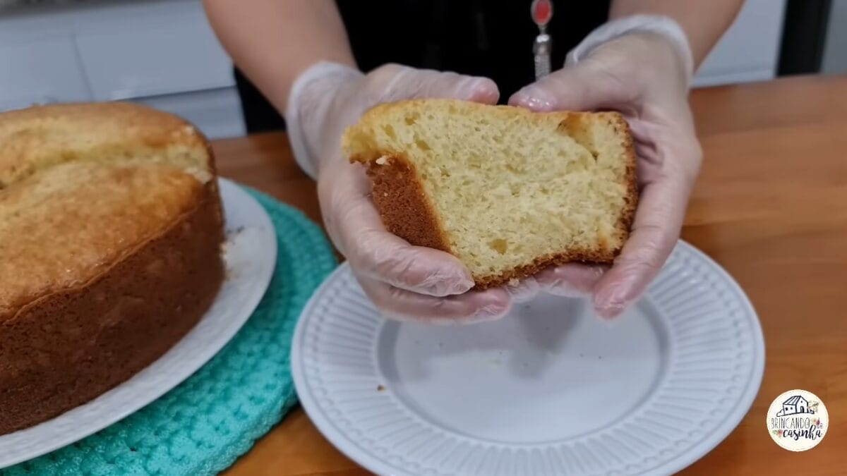 Fatia de bolo de amido de milho segurada com as m&atilde;os destacando miolo &uacute;mido