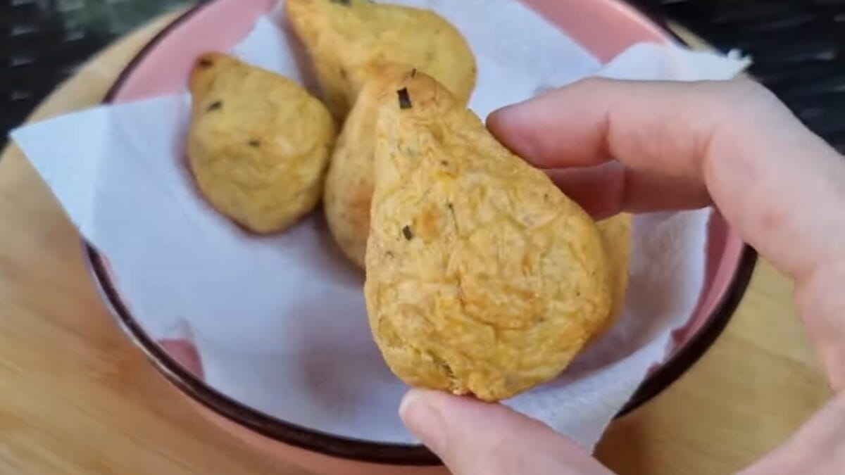 Coxinha fit de batata sendo segurada, mostrando textura dourada e crocante feita na air fryer.