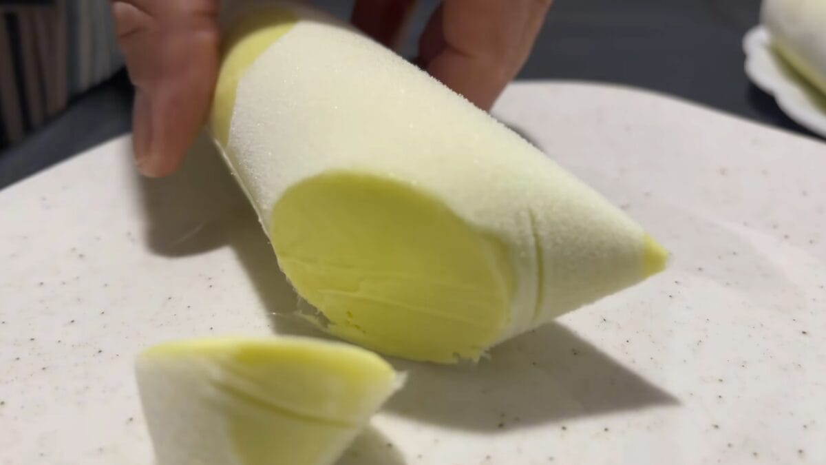 Geladinho de abacate cortado ao meio revelando consist&ecirc;ncia cremosa ap&oacute;s congelamento