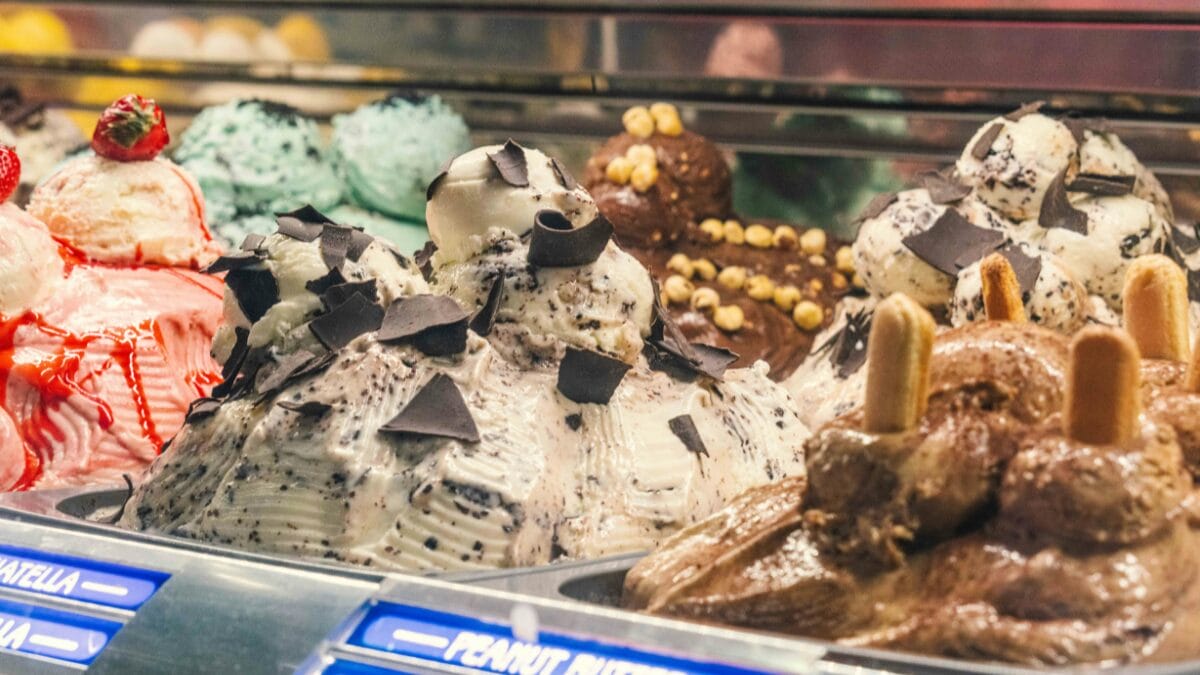 Vitrine com diferentes sabores de gelato italiano artesanal exibidos em balc&atilde;o refrigerado
