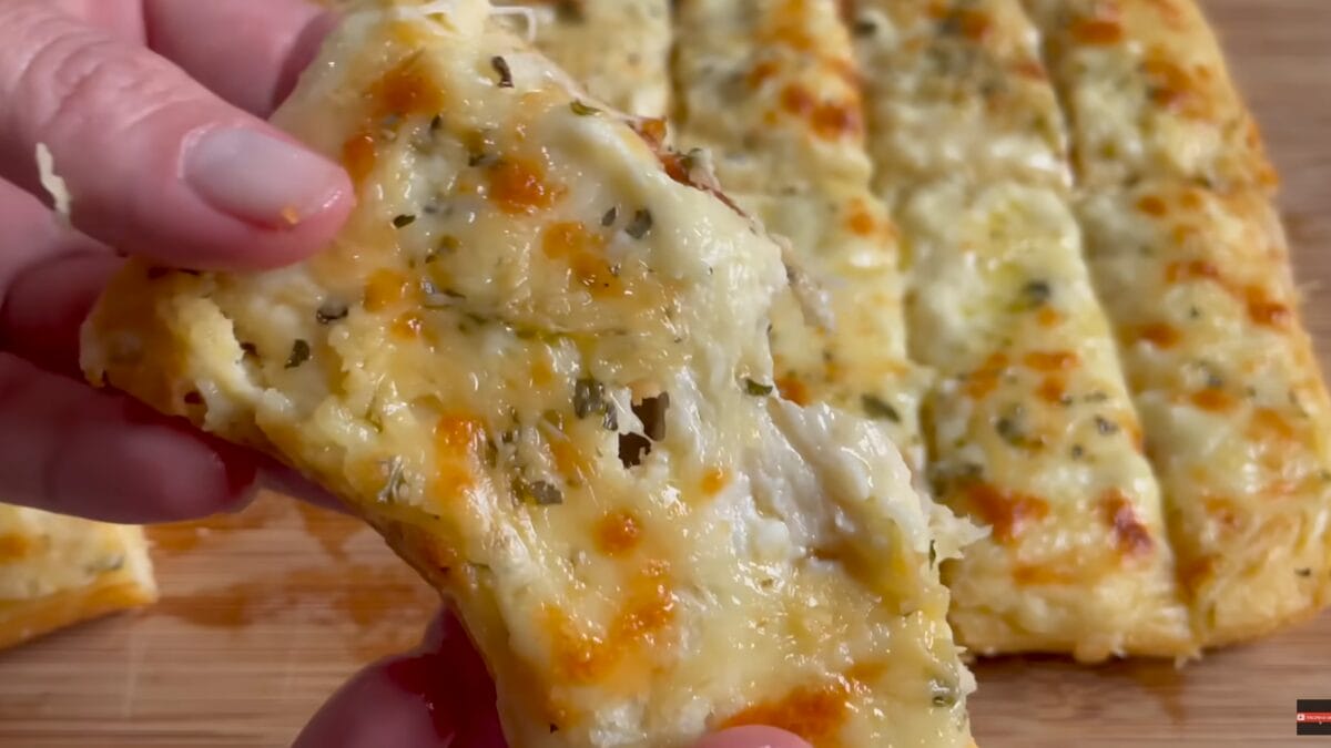 Massa low carb de frango com queijo derretido sendo puxada em close