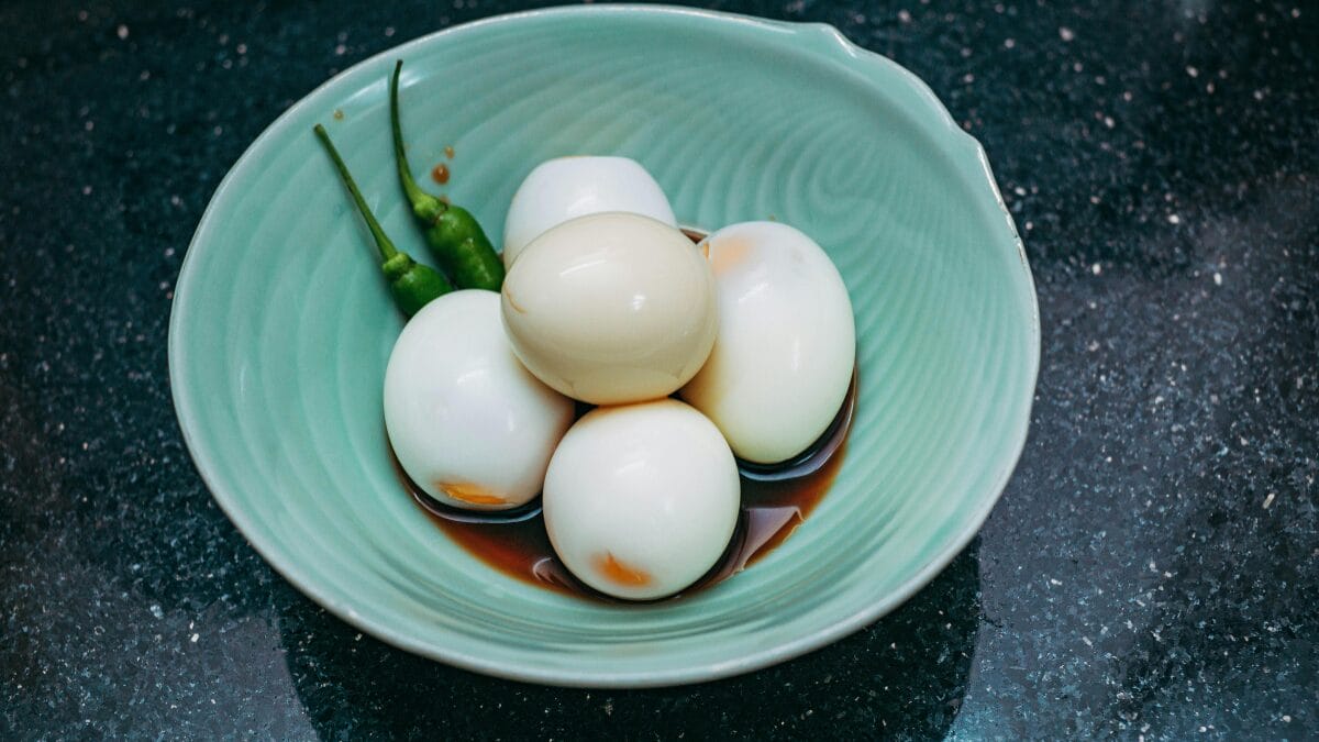 Ovos cozidos descascados servidos em tigela com temperos ap&oacute;s preparo na airfryer