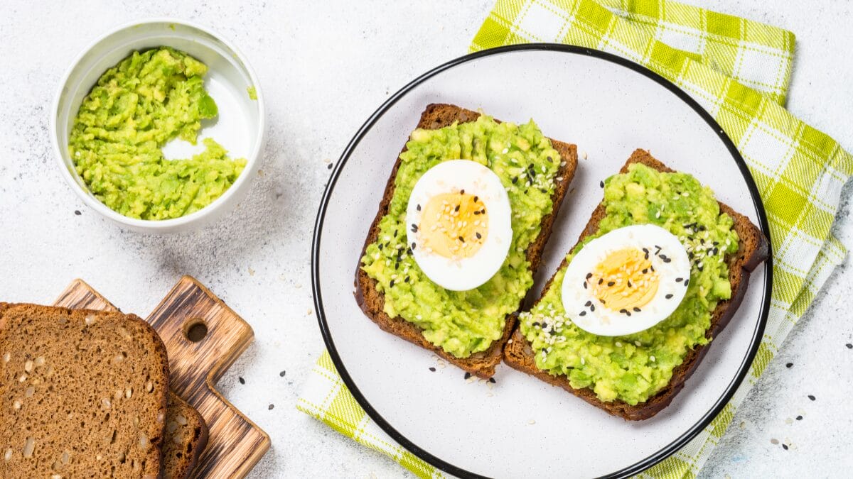 Ovo cozido fatiado servido sobre torrada com pasta verde em refei&ccedil;&atilde;o leve