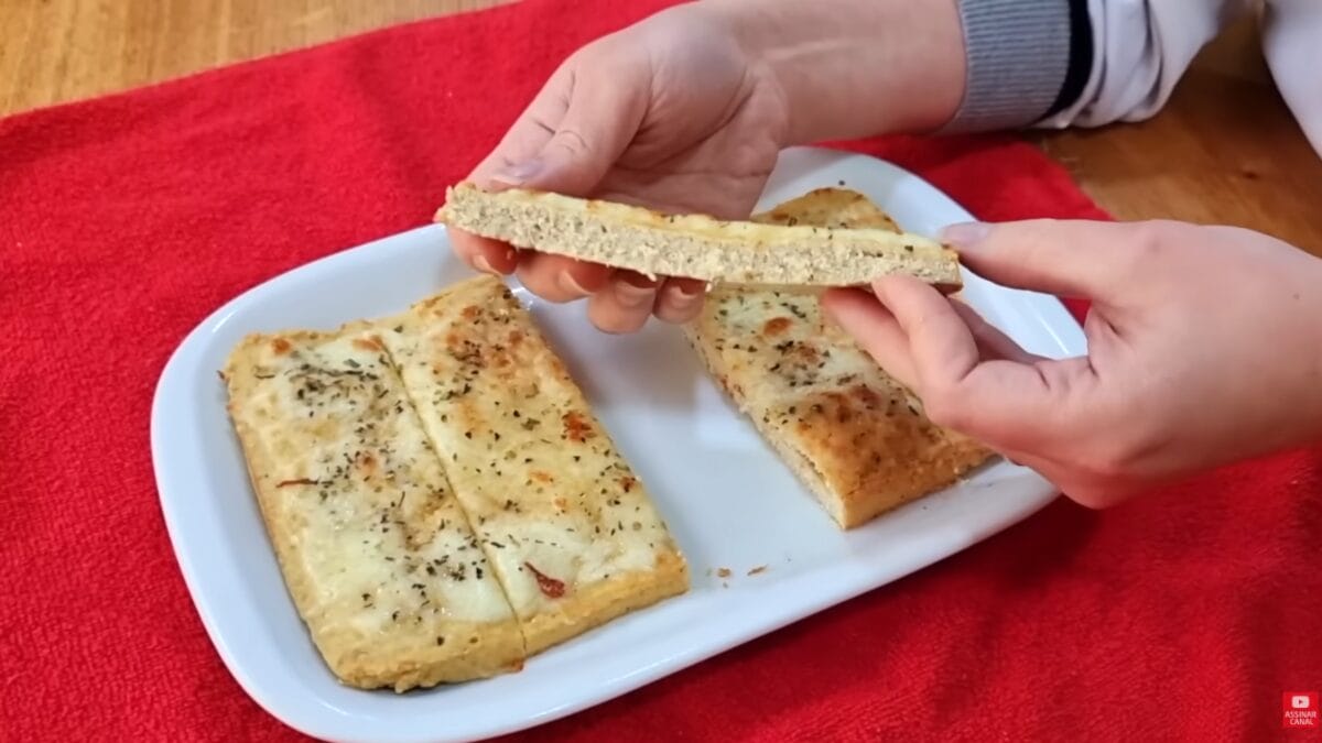 Pão sem carboidratos assado e fatiado com cobertura gratinada sendo mostrado em prato branco