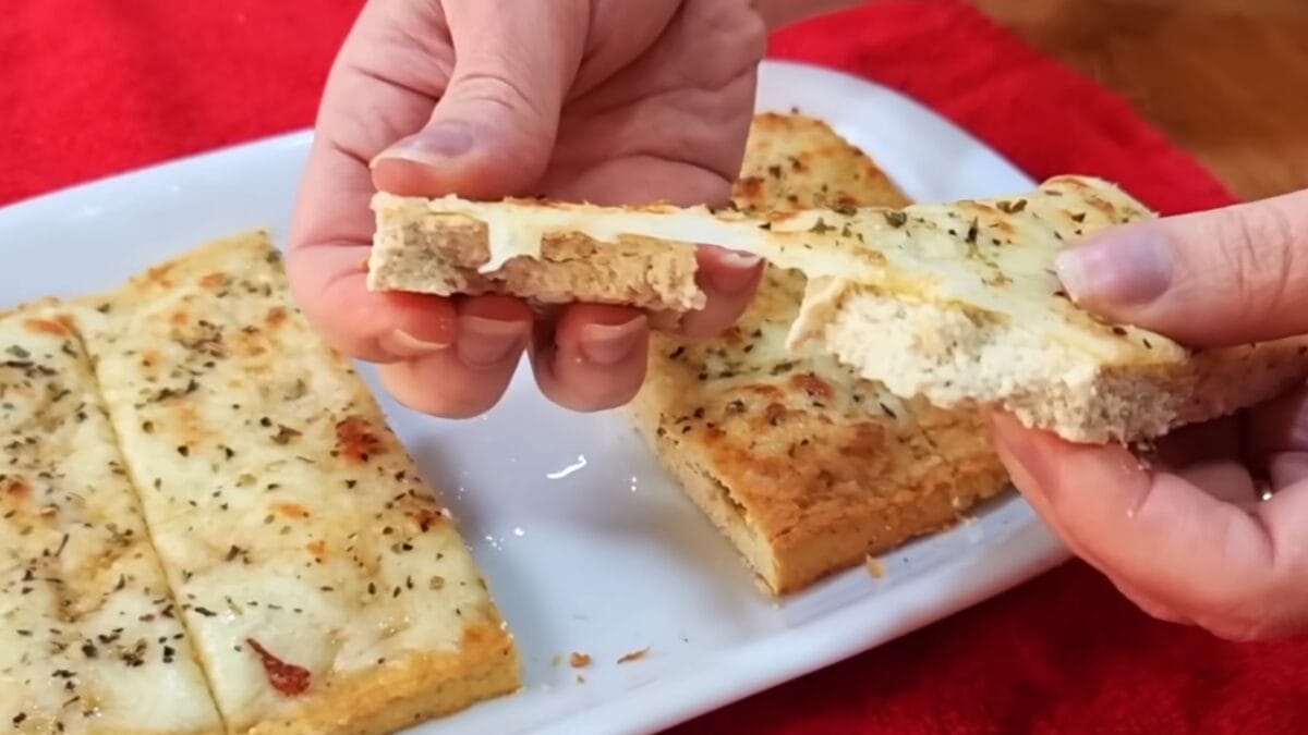 Fatia de pão sem carboidratos partida ao meio mostrando interior macio e estrutura da massa