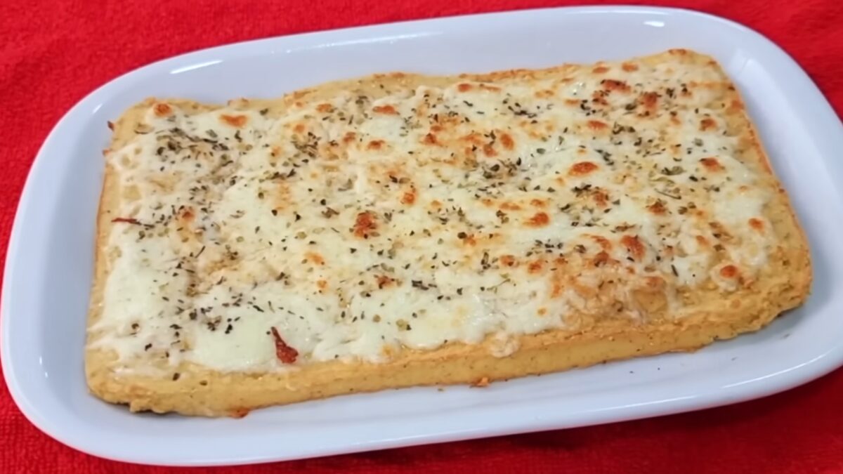 Pão sem carboidratos inteiro com cobertura de queijo e ervas servido em travessa branca