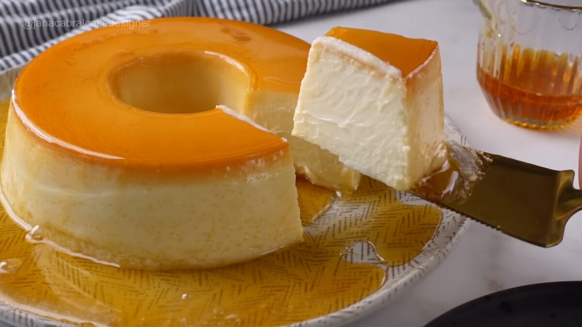 Fatia de pudim de iogurte sendo retirada com esp&aacute;tula, mostrando interior cremoso