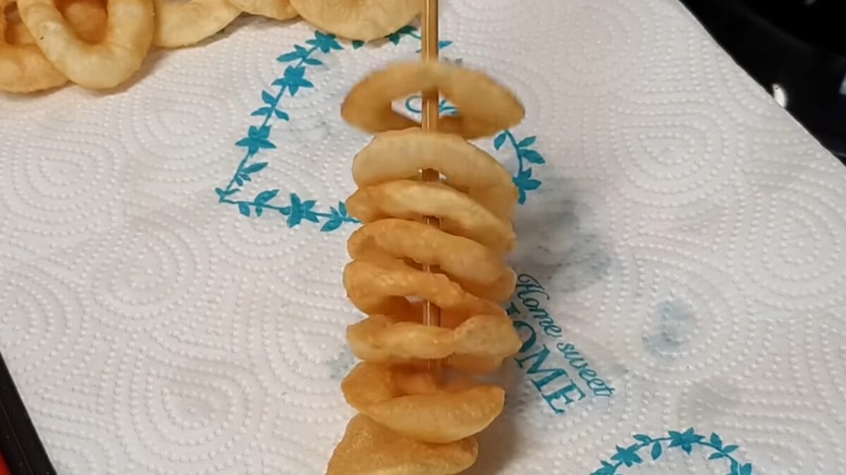 Salgadinhos crocantes escorrendo óleo em papel-toalha após fritura