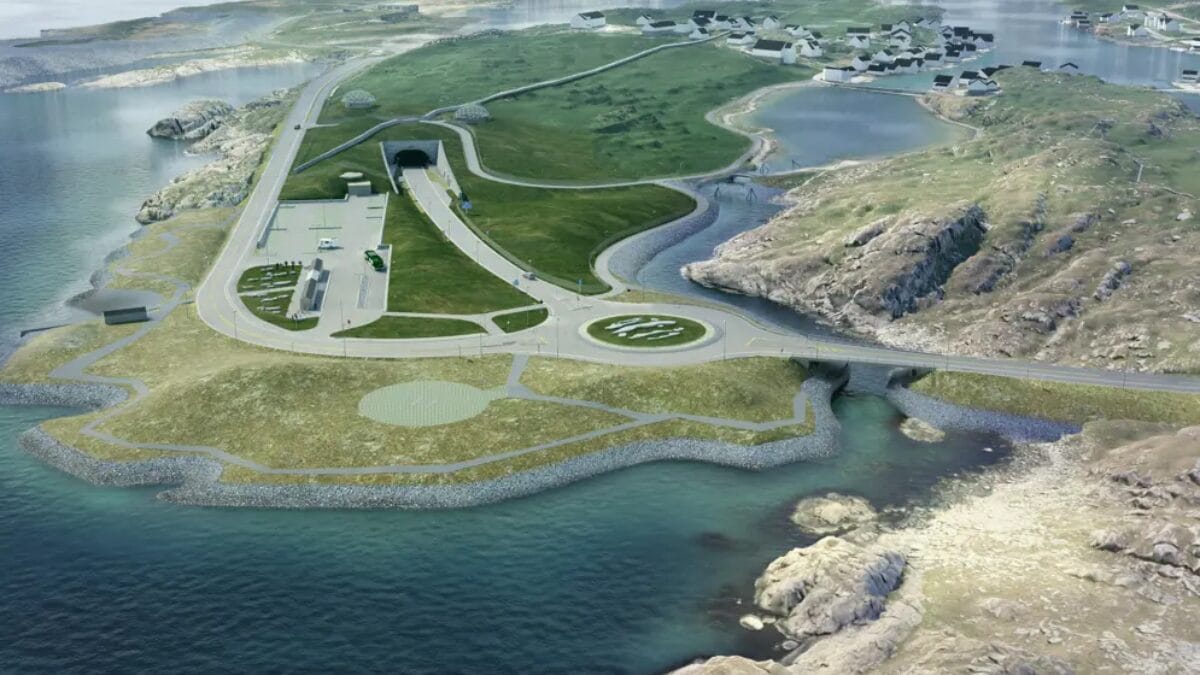 Renderiza&ccedil;&atilde;o de uma entrada de t&uacute;nel em uma encosta gramada. H&aacute; uma rotat&oacute;ria em primeiro plano, uma pequena &aacute;rea de estacionamento &agrave; esquerda e uma ponte conectando partes da ilha sobre o mar.