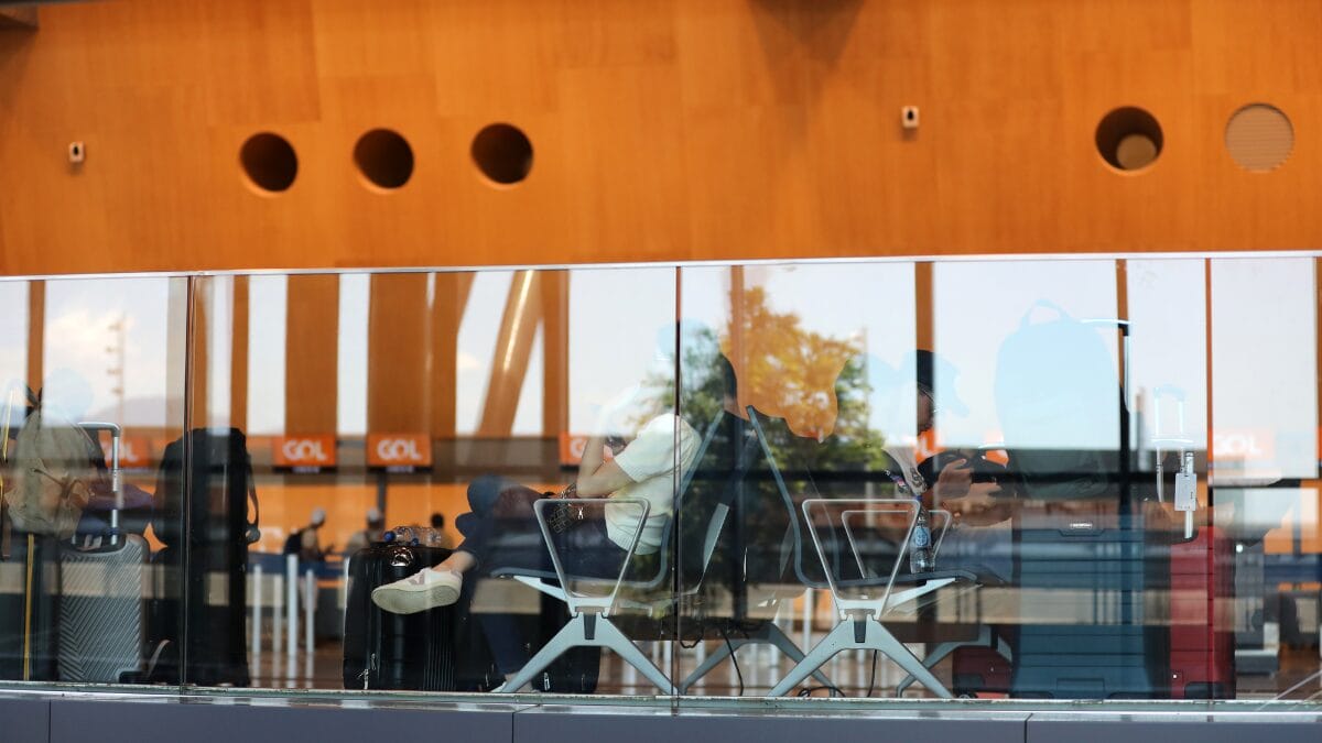 Área de espera do terminal de passageiros do Aeroporto Internacional de Florianópolis, vista através de divisória de vidro.