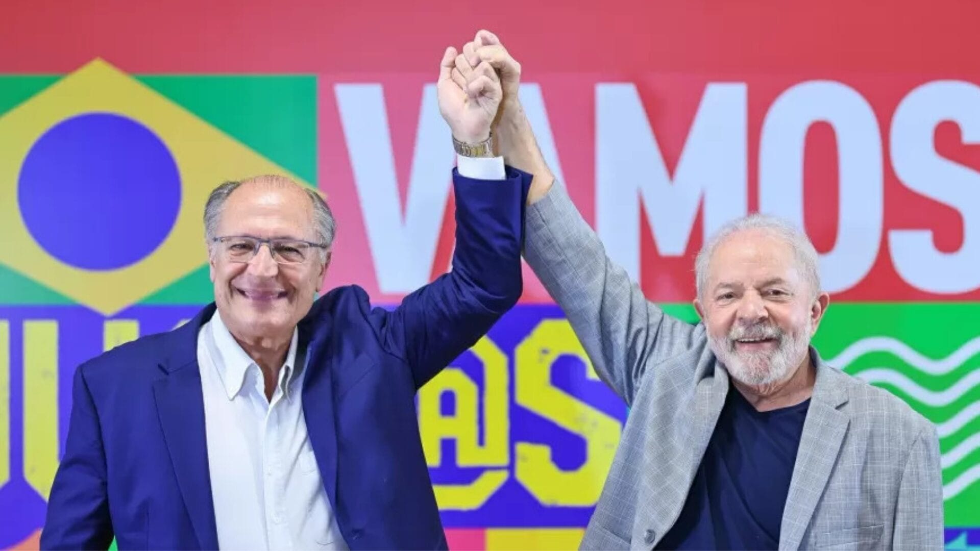 Lula e Alckmin sorriem enquanto dão as mãos