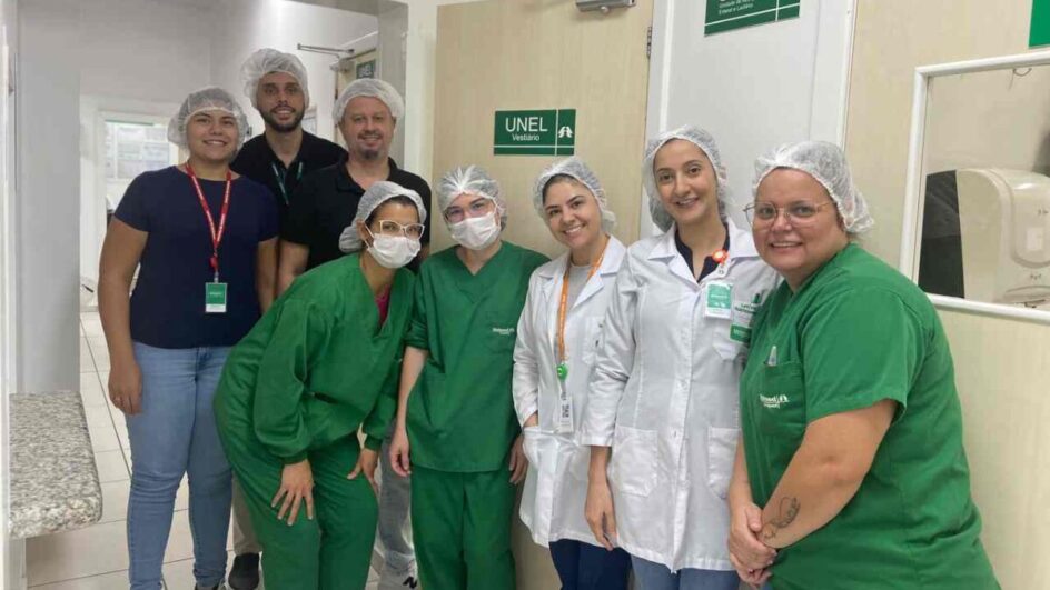 Grupo de sete profissionais de saúde da Unimed Chapecó, vestindo uniformes hospitalares e toucas