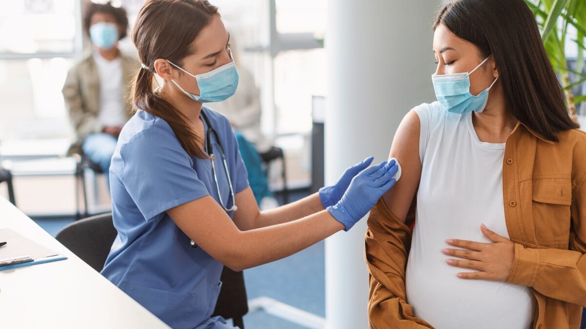 Profissional da sa&uacute;de aplica vacina em gestante