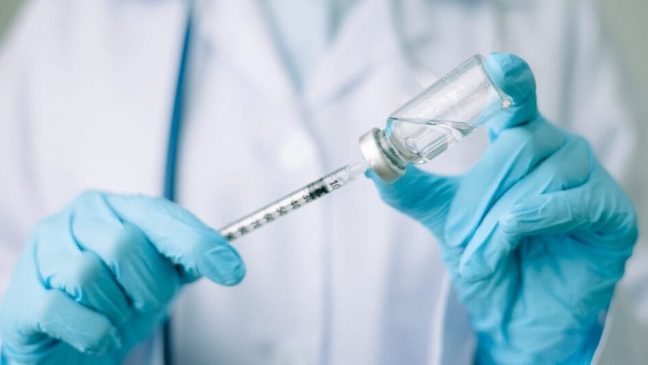 Profissional da saúde usa luvas e se prepara para aplicar vacina.