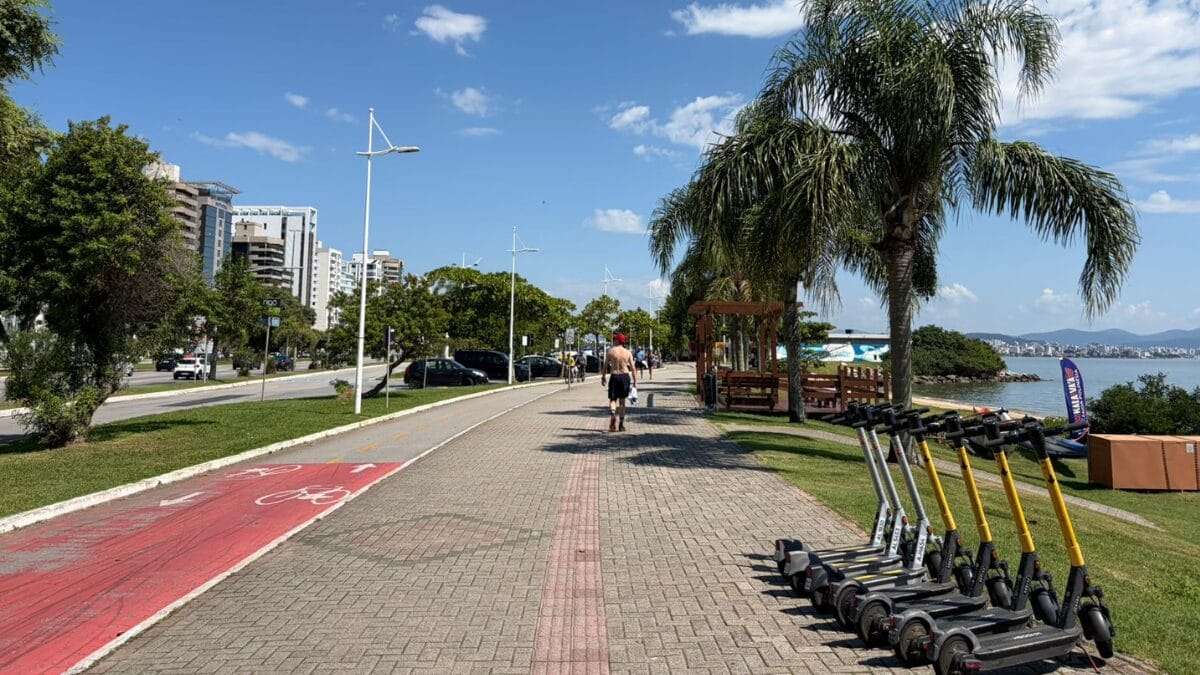 Ciclovia da Beira-Mar Norte com patinetes el&eacute;tricos estacionados e &aacute;rea verde &agrave;s margens da avenida, em Florian&oacute;polis.