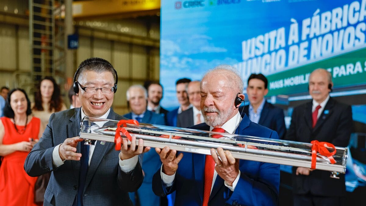 Presidente Lula e representante da CRRC exibem modelo de trem em evento com autoridades e empres&aacute;rios.