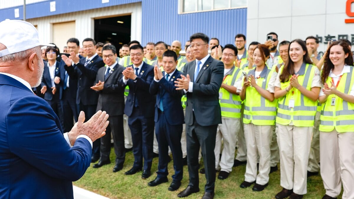 Funcion&aacute;rios com coletes de seguran&ccedil;a aplaudem o presidente em frente &agrave; f&aacute;brica da CRRC.