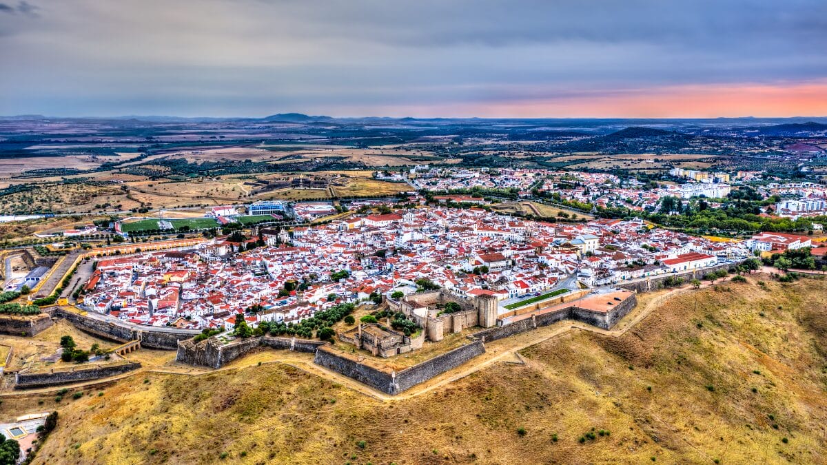 Vista a&eacute;rea das casas brancas com telhados vermelhos do centro hist&oacute;rico de Elvas, cercadas por muralhas defensivas em formato de estrela.