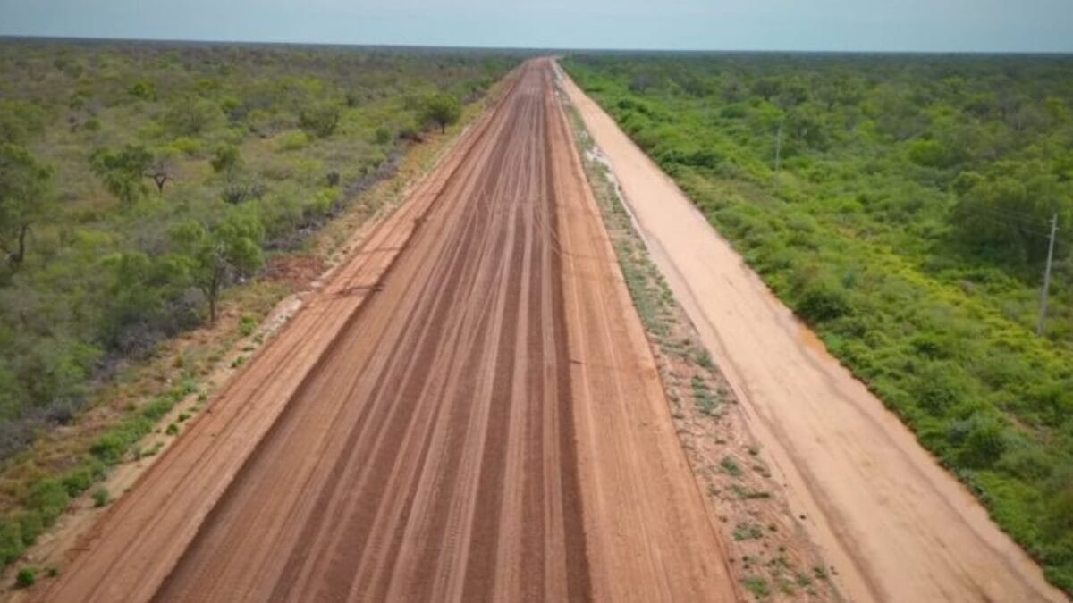 Estrada em fase de implanta&ccedil;&atilde;o corta &aacute;rea rural com vegeta&ccedil;&atilde;o dos dois lados.