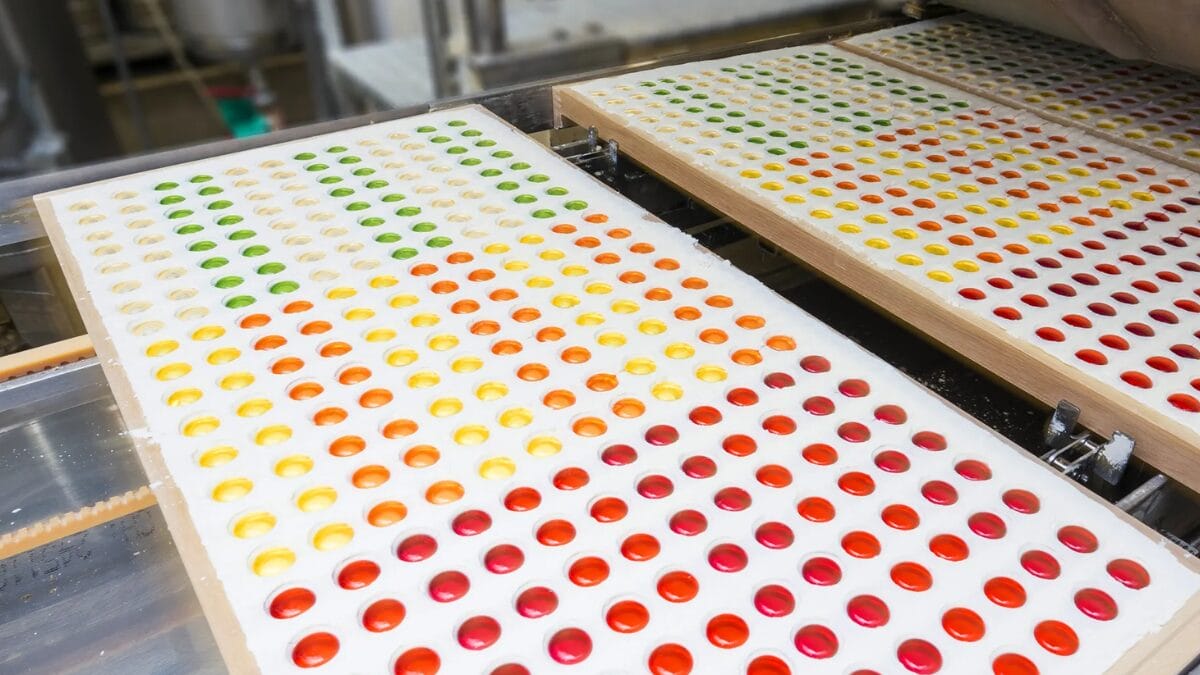 Moldes preenchidos com balas de gelatina aparecem dispostos em fileiras na ind&uacute;stria.