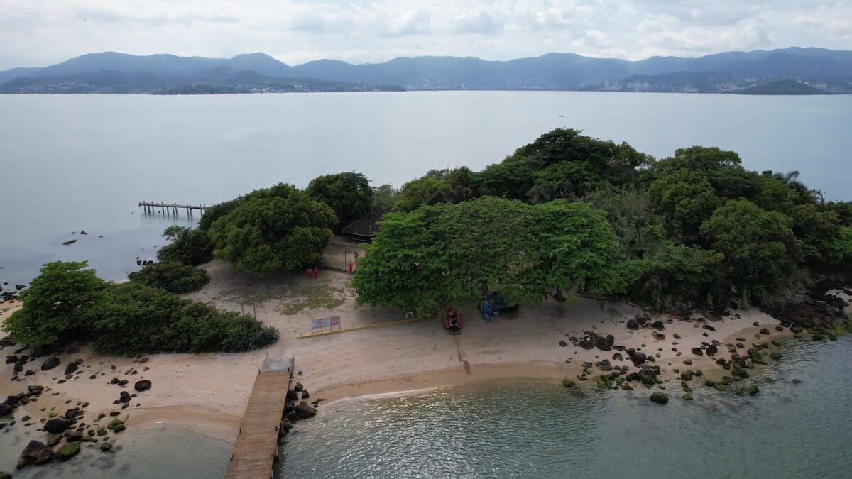 Ilha dos Guar&aacute;s Grande vista do alto, com o mar ao redor e o continente de Florian&oacute;polis ao fundo.