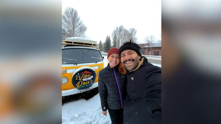 casal de viajantes tira foto em frente a Kombi no Alasca