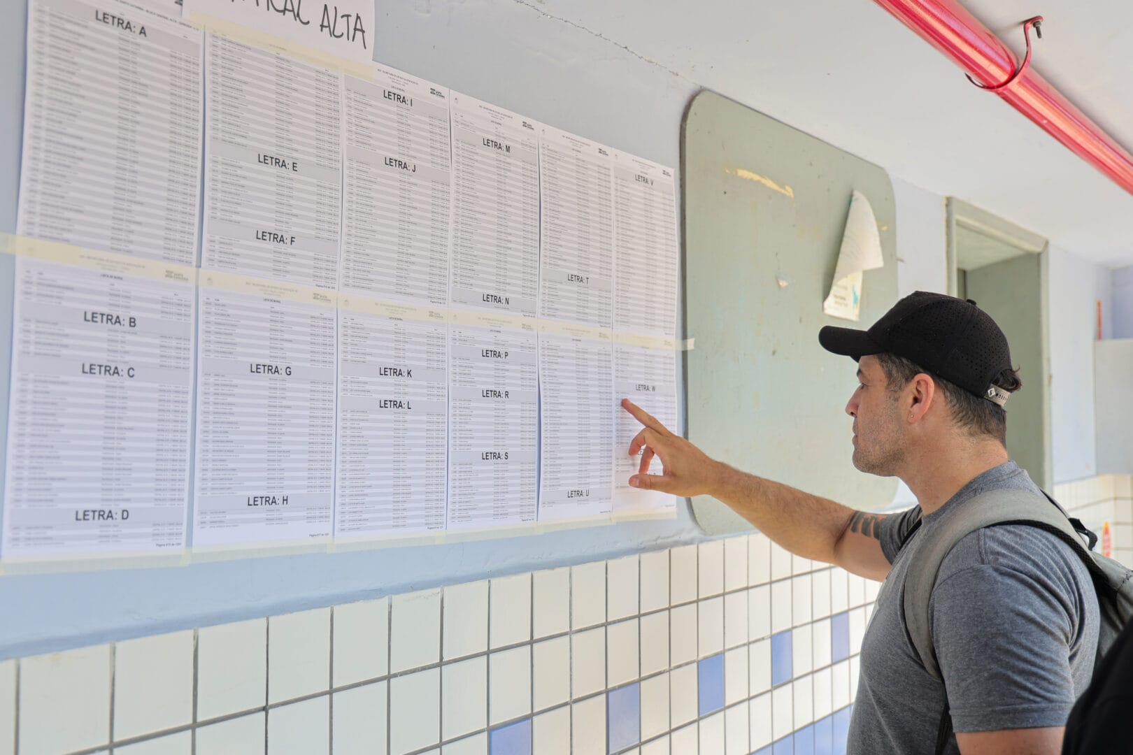 pessoa busca seu nome na lista de pessoas aptas a fazerem a prova