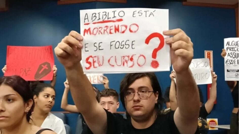 aluno segura cartaz escrito "a biblio está morrendo e se fosse o seu curso?"