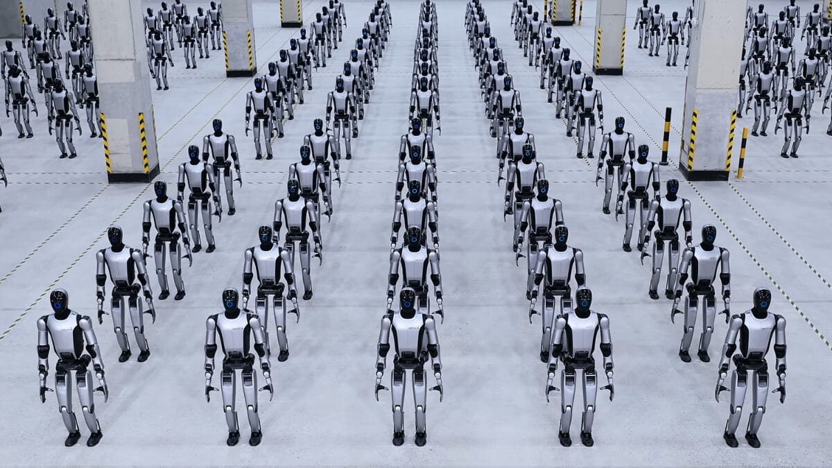Vista a&eacute;rea de dezenas de rob&ocirc;s humanoides da UBTECH organizados em linhas sim&eacute;tricas no interior de um grande galp&atilde;o industrial.