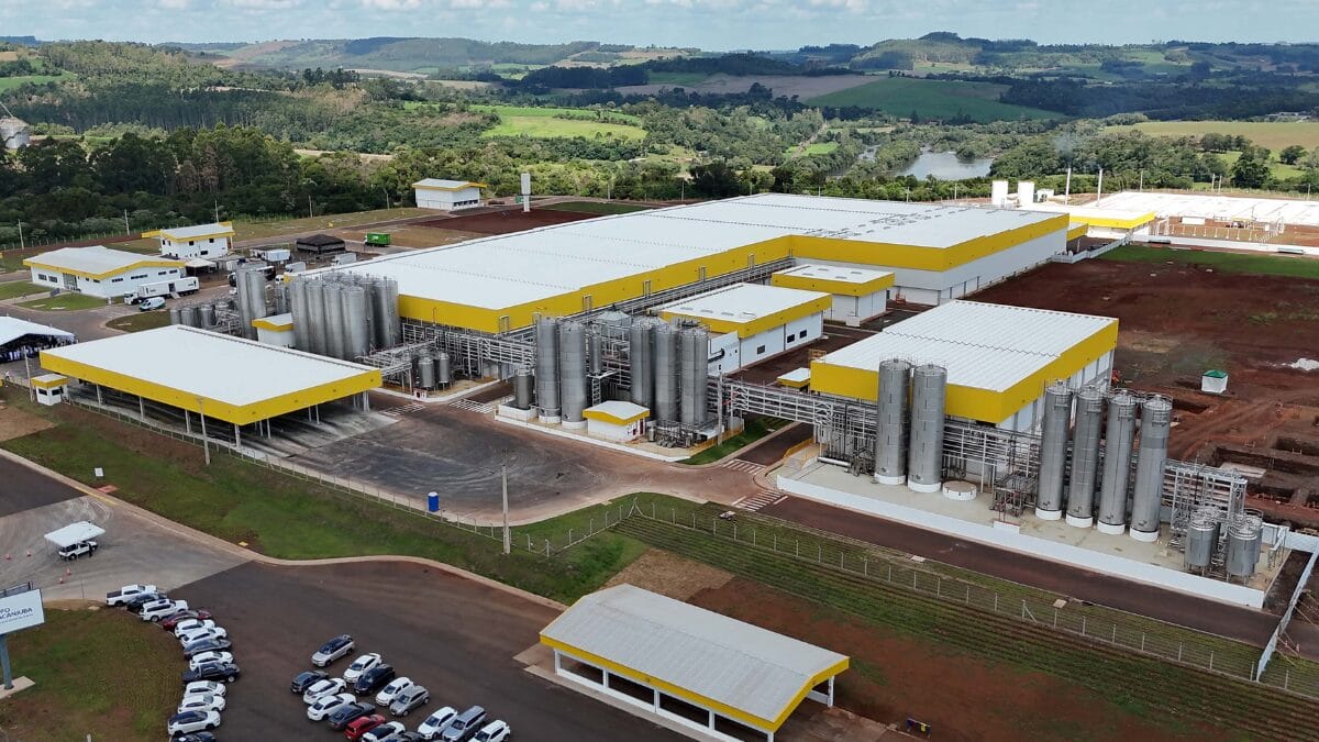 Vista a&eacute;rea ampla da f&aacute;brica com galp&otilde;es, tanques e vias internas.