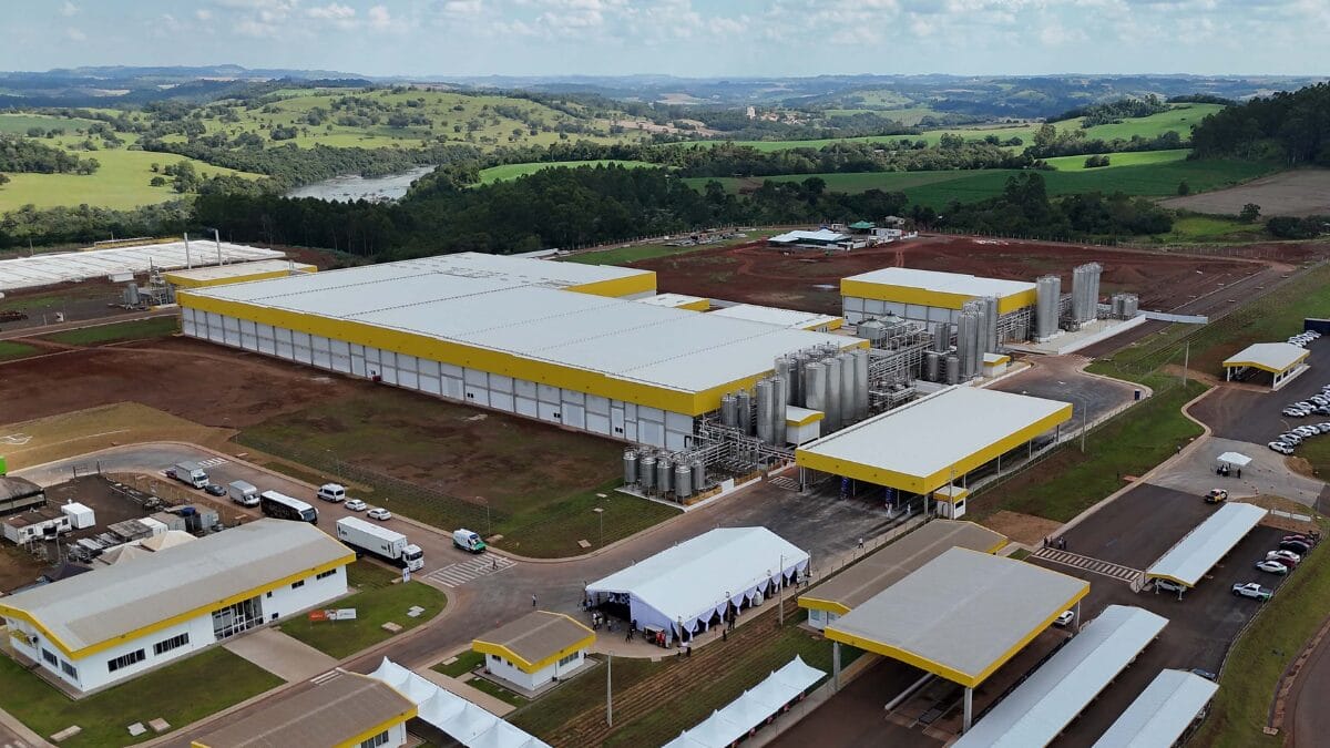 Vista a&eacute;rea ampla da f&aacute;brica com galp&otilde;es, tanques e vias internas.