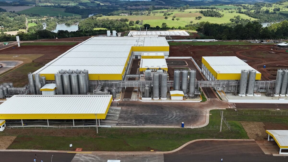 Imagem a&eacute;rea da f&aacute;brica de latic&iacute;nios cercada por &aacute;reas verdes e estrutura industrial completa.