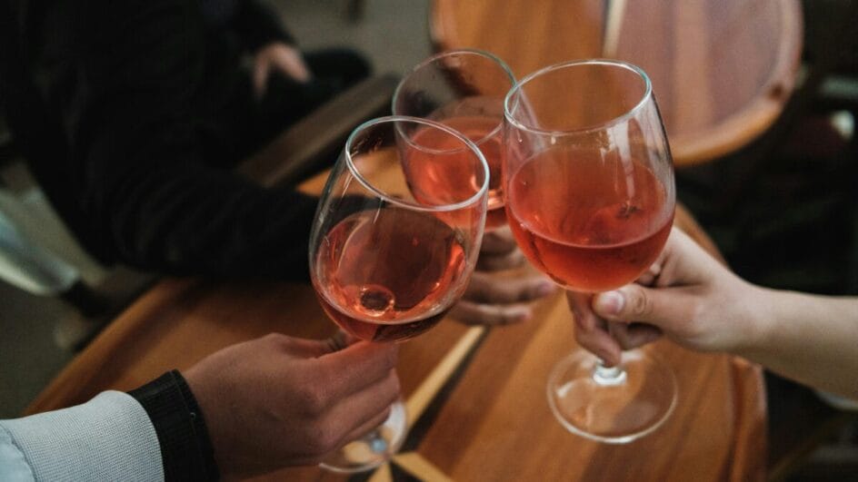 Pessoas brindando com taças de vinho rosé