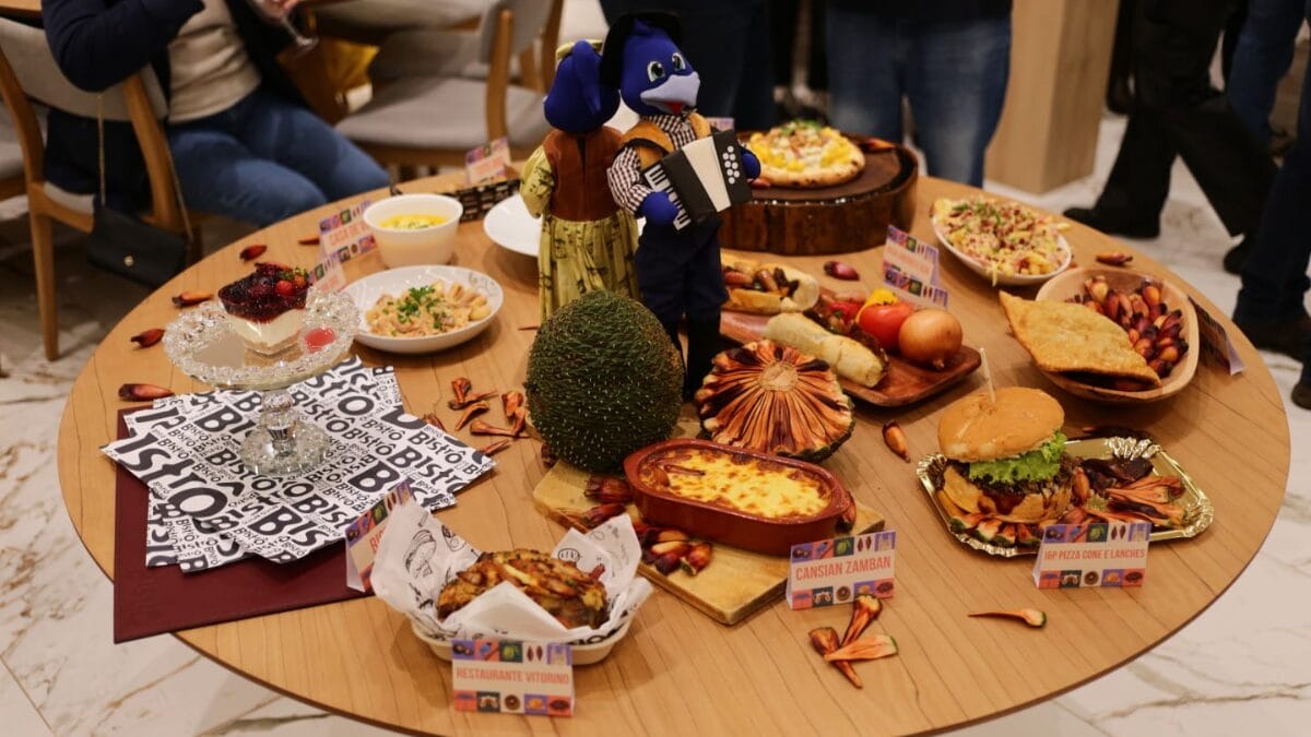 Pratos apresentados no Festival Sabores da Serra, dispostos em uma mesa redonda com um enfeite de gralhas no centro