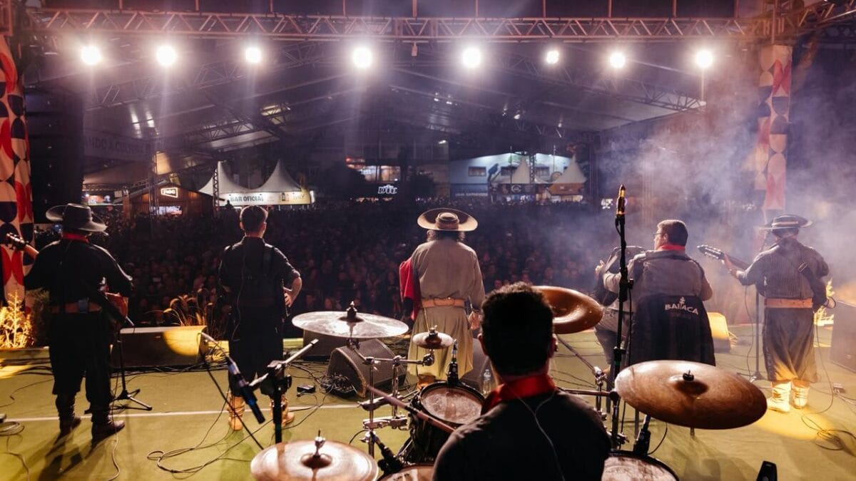 Cantor Baitaca e quatro integrantes de sua banda vistos de trás do palco