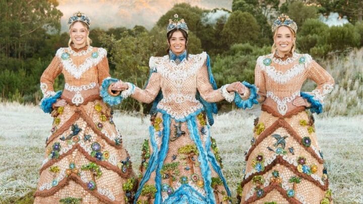 rainha e princesas da Festa do Pinhão, em um campo, vestindo os trajes oficiais