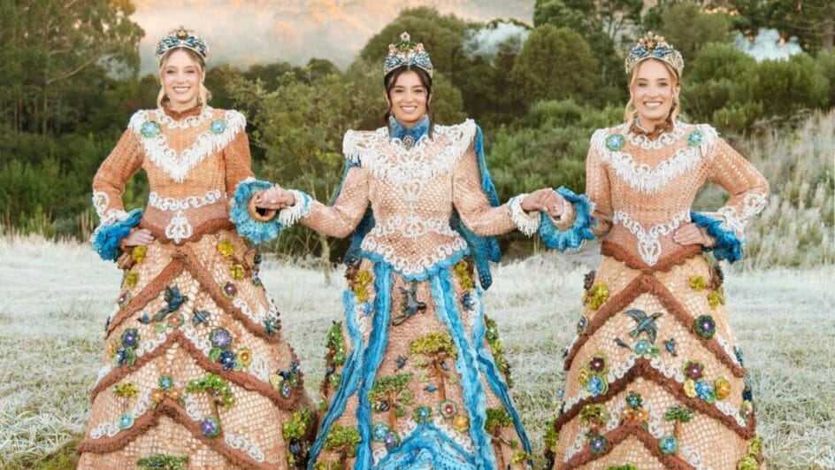 rainha e princesas da Festa do Pinhão, em um campo, vestindo os trajes oficiais