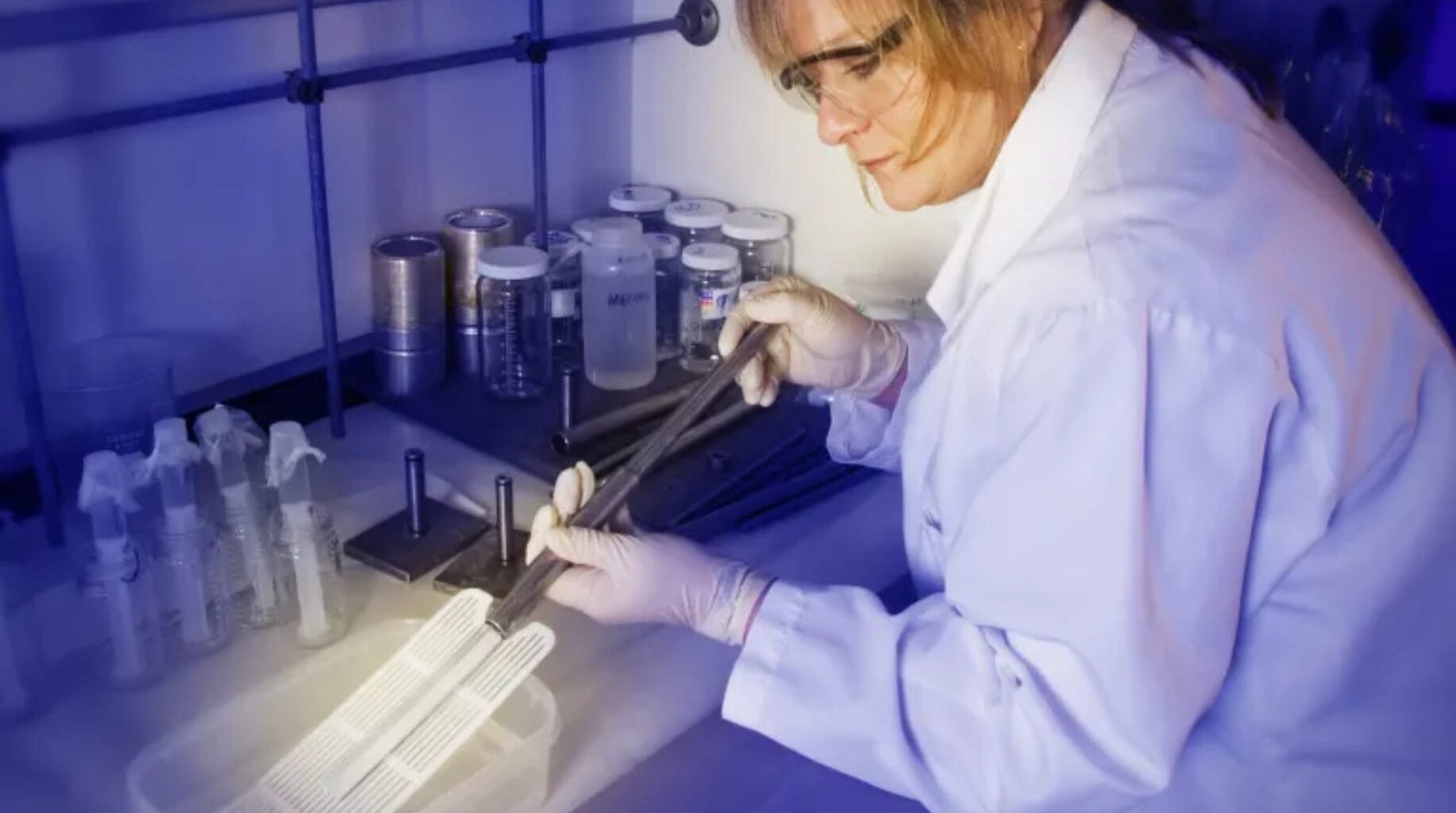 Cientista em laboratório manipulando amostra de aerogel com pinça