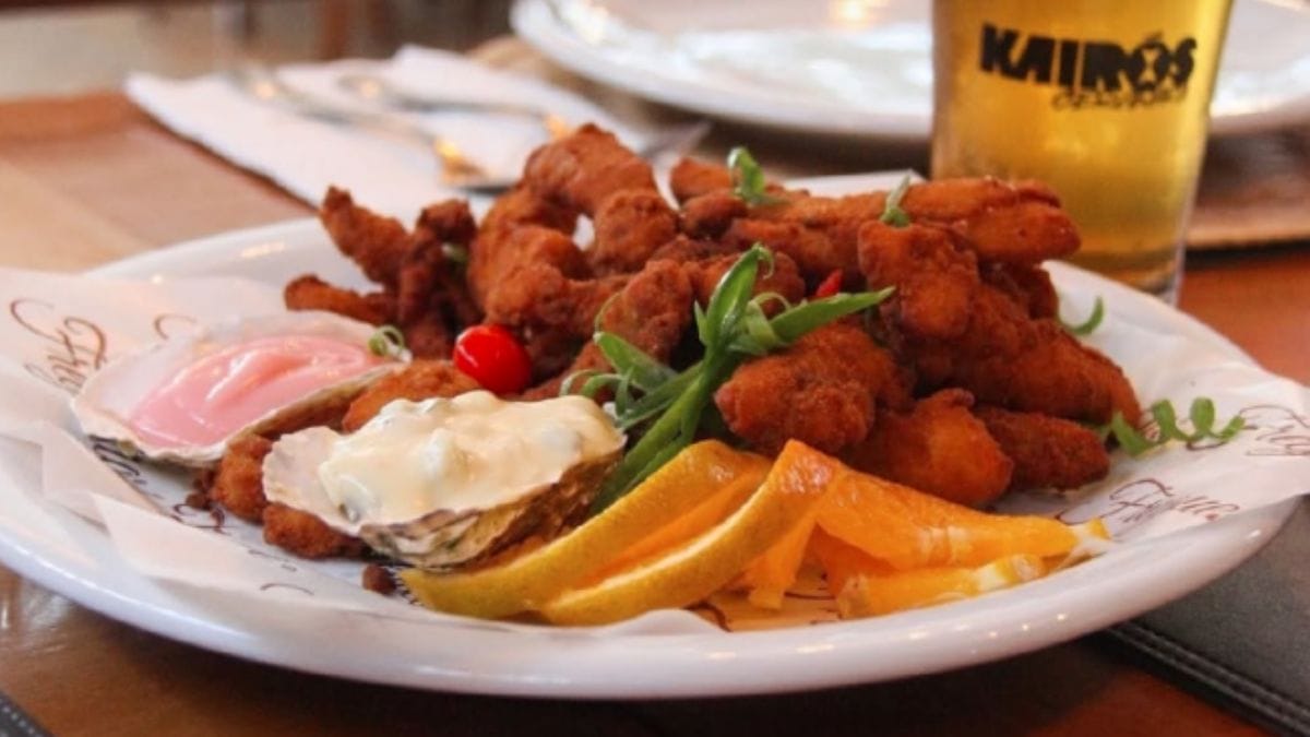 Prato de frutos do mar empanados e fritos com ostras e ao fundo, um copo de chopp, do Freguesia Oyster Bar.