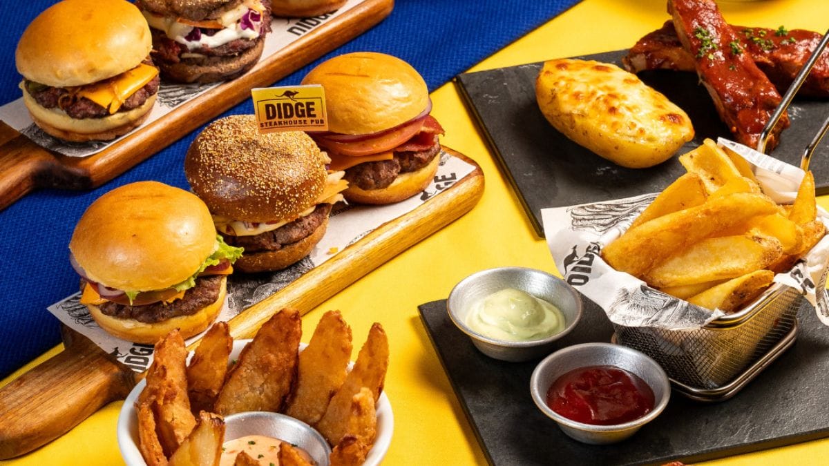 Mesa farta com hambúrgueres, molhos, porções de fritas e empanados, do Didge Steakhouse Pub.