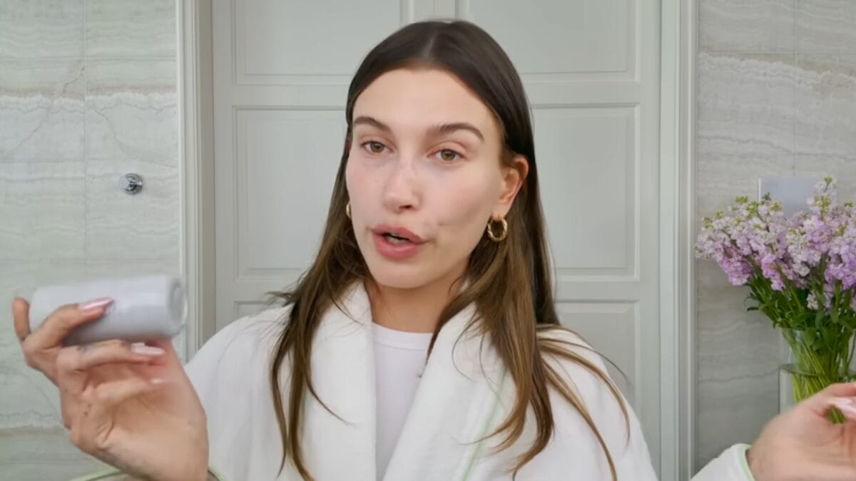 Hailey Bieber segura produto de skincare durante rotina de cuidados com a pele.
