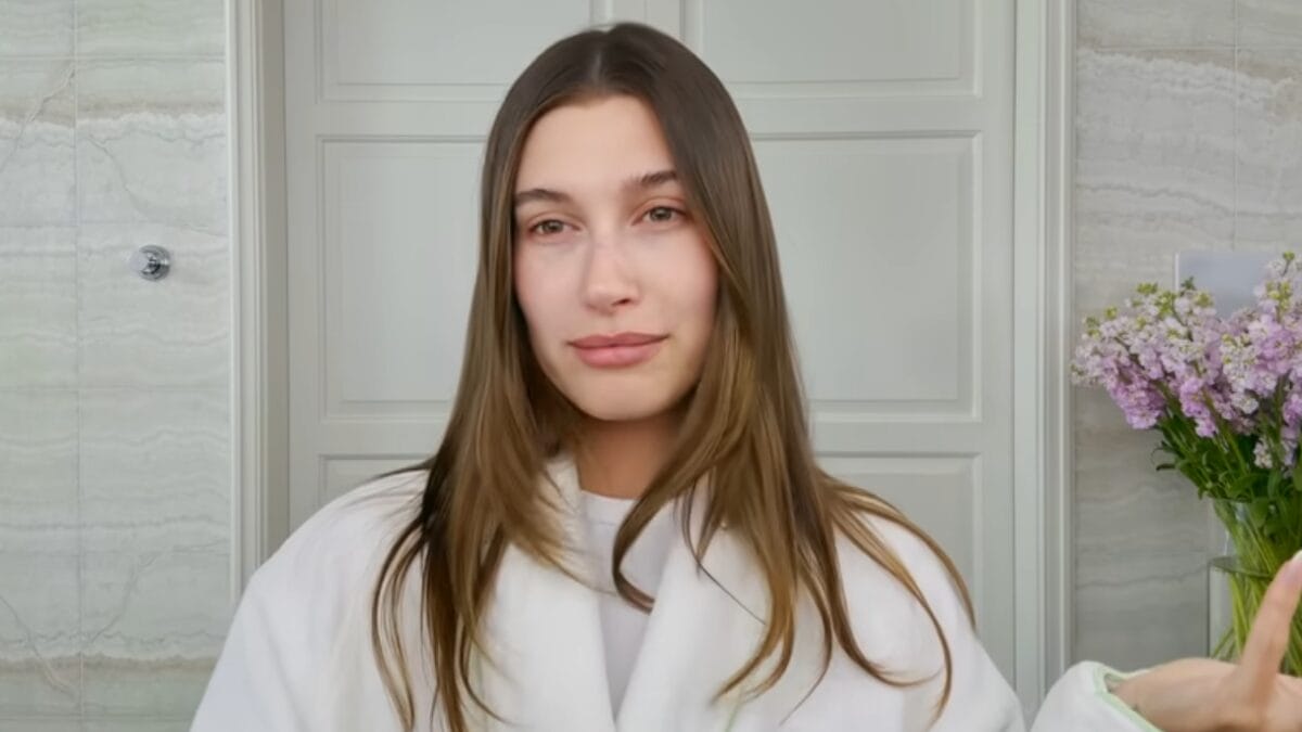 Hailey Bieber aparece sem maquiagem em banheiro claro durante v&iacute;deo sobre rotina de beleza matinal.